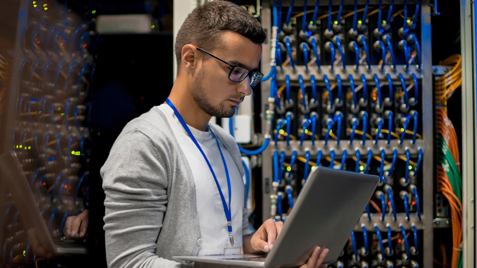 IT guy studying a laptop next to high-end data patch panel