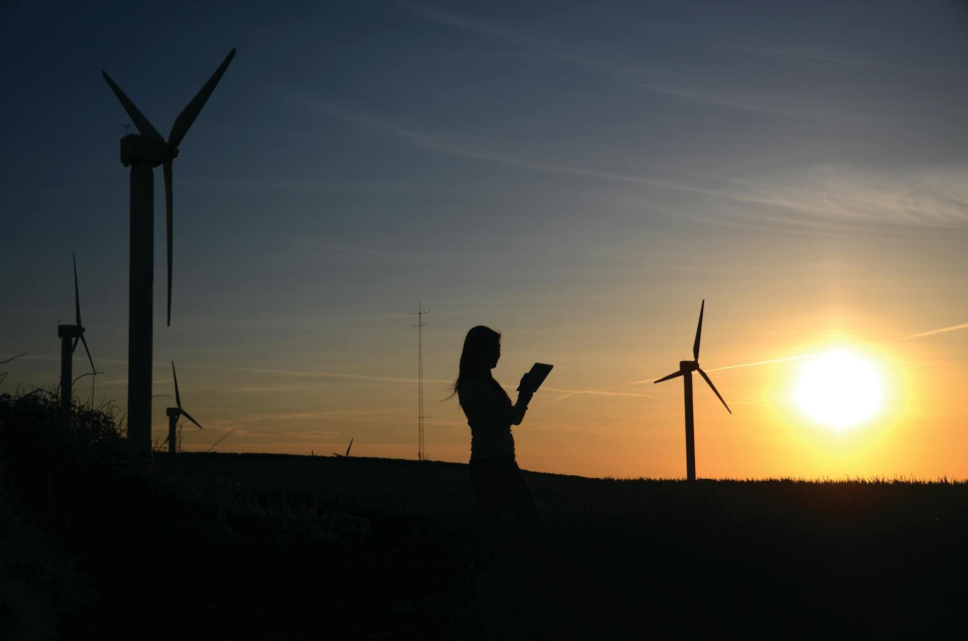 Girl in a sunflower field with wind turbines in the background
